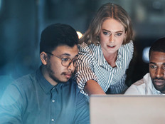 Three people looking at a laptop screen.