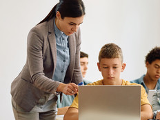 teacher helping students use laptops for school lessons