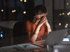 Woman sitting in front of a laptop looking concerned late at night