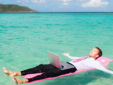 Person floating in the ocean while working on a computer
