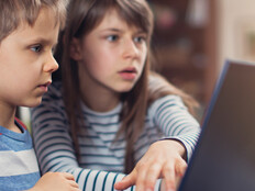 Two K–12 students working on a school laptop together