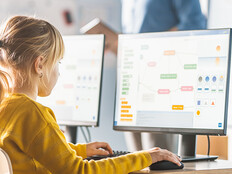 Kids in a classroom viewing the same information on their own monitors.