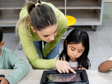 Teacher helping students using tablets