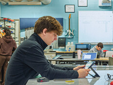 Student in a classroom working on a tablet at a table