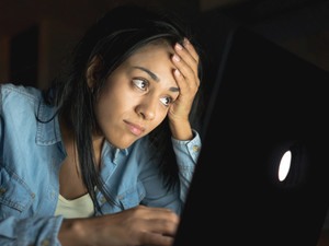 student sitting in the dark looking upset at computer screen