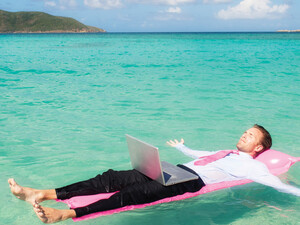 Person floating in the ocean while working on a computer