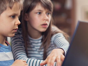 Two K–12 students working on a school laptop together