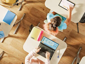 Overhead view of children sitting at desks working in a classroom on computers