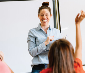A teacher in the front of a classroom teaching students.