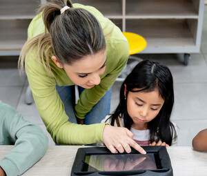 Teacher helping students using tablets